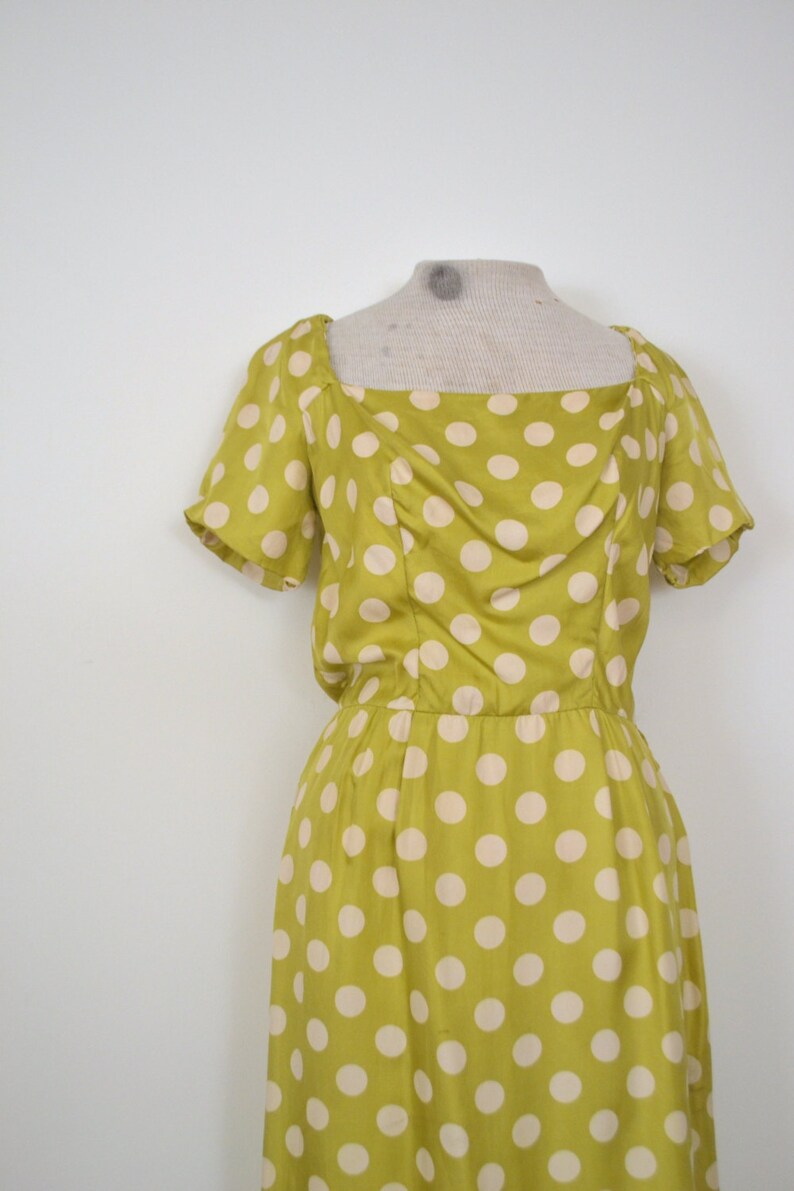 May include: A yellow dress with white polka dots. The dress has a square neckline and short sleeves.