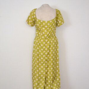May include: A green midi dress with white polka dots. The dress has a square neckline and short puff sleeves.