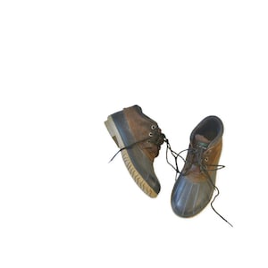 Puede incluir: Un par de botas de invierno marrones y negras con cordones. Las botas tienen una suela de goma y una parte superior de gamuza.