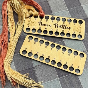 May include: Two wooden thread organizers with alphabet labels. The top organizer has the text "Pam's Pretties" printed on it.