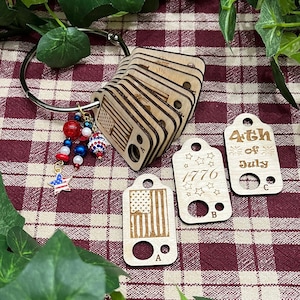 May include: Wooden tags with a red, white, and blue American flag design, the text "4th of July", "1776", and the letters "A", "B", and "C".