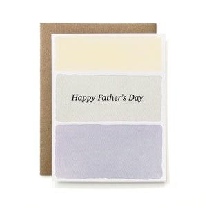 May include: A white card with a light yellow, gray, and light purple watercolor design. The card says "Happy Father's Day" in black text.