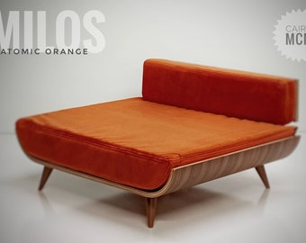 May include: A low-profile daybed featuring a vibrant orange upholstered cushion and a curved wooden frame with tapered legs. The text MILOS ATOMIC ORANGE and CAIRU MCM is visible in the upper corners of the image, describing the furniture piece.