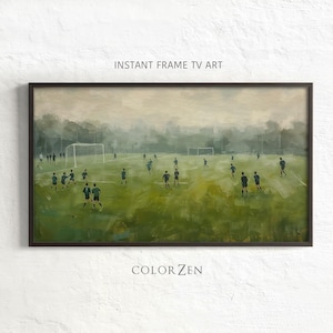 May include: Framed artwork depicting a soccer game in progress. The painting features players in dark uniforms on a green field, with goals at each end. The text "INSTANT FRAME TV ART" and "COLOR ZEN" are visible.