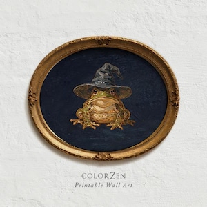 Puede incluir: Un marco ovalado dorado y ornamentado que contiene una pintura de una rana verde con un sombrero negro puntiagudo sobre un fondo azul oscuro. Debajo del marco, el texto dice COLOR ZEN Printable Wall Art en una fuente gris oscuro simple.