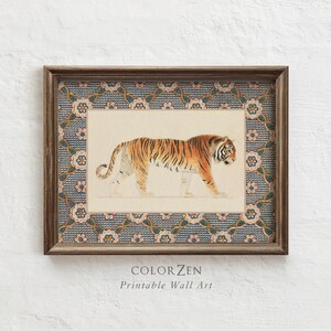 Può includere: Opera d'arte da parete incorniciata con un dipinto ad acquerello di una tigre a strisce arancioni e nere. L'opera è ambientata su uno sfondo color crema e incorniciata con un bordo decorativo blu e floreale. Il testo "COLORZEN Printable Wall Art" è in basso.