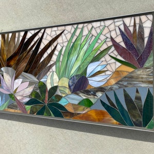 May include: A colorful mosaic wall art featuring a variety of plants and flowers. The artwork is made of small pieces of glass in shades of brown, green, blue, purple, and white.