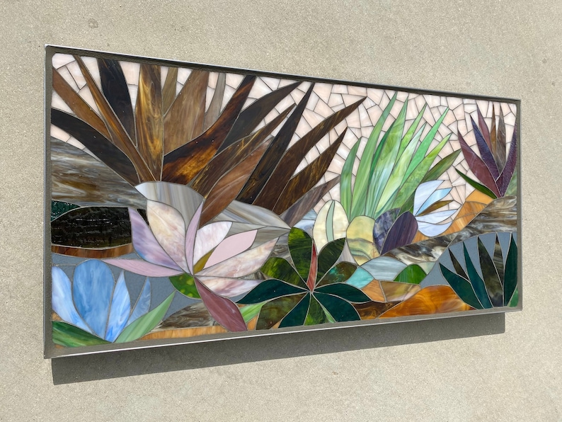 May include: A rectangular stained glass mosaic wall art featuring a variety of plants and flowers in shades of brown, green, blue, pink, and purple.