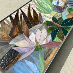 May include: A rectangular mosaic table top with a floral design. The design features pink, blue, green, and brown glass tiles arranged in a pattern of flowers and leaves.