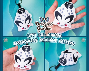 May include: A white and gray plush charm with a black and white design. The charm is shaped like a creature with a round body, two large eyes, and a small mouth. The charm is attached to a silver key ring. The charm is labeled "(iTH) 4X4 CHARM EMBROIDERY MACHINE PATTERN".