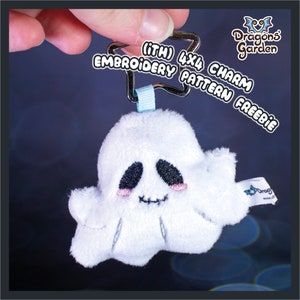 May include: A white plush ghost charm with black eyes and a stitched mouth. The charm is attached to a silver star-shaped keyring with a blue ribbon. The text "(ITH) 4x4 CHARM EMBROIDERY PATTERN FREEBIE" is written in white on a black background.