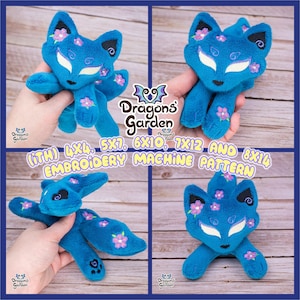 May include: A blue plush fox with pink flowers embroidered on it. The fox is sitting on a wooden surface. The text "Dragons Garden (iTH) 4x4, 5x7, 6x10, 7x12 AND 8x14 EMBROIDERY MACHINE PATTERN" is visible in the image.