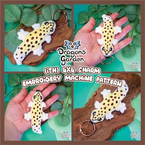 May include: A plush leopard gecko keychain with a yellow body, brown spots, and white accents. The keychain has a metal ring and is displayed on a piece of wood. The image includes the text "Dragons' Garden" and "(ITH) 4X4 CHARM EMBROIDERY MACHINE PATTERN."