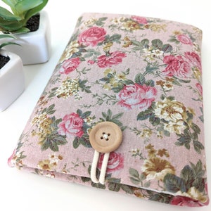 May include: A pink floral fabric pouch with a wooden button closure. The pouch is made of a soft, cotton fabric and has a vintage floral print.