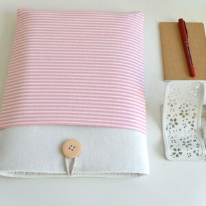 Op de afbeelding: Een roze en wit gestreepte laptophuls met een beige klep en een houten knoopsluiting.