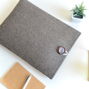 May include: A gray felt laptop sleeve with a brown button closure.