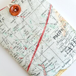 May include: A vintage map of the Pacific Ocean with red and green lines marking routes and distances. The map is printed on a cream-colored background with brown text and is folded in half. A brown button is attached to the top of the map.
