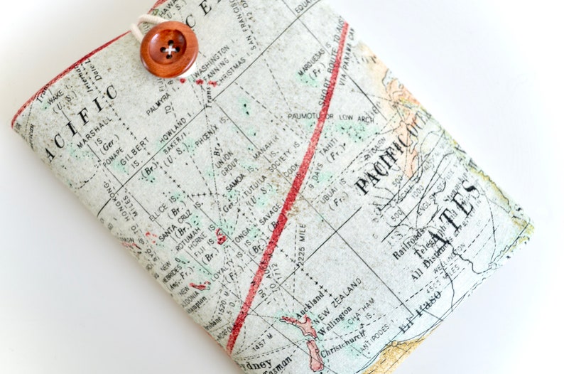May include: A vintage map of the Pacific Ocean with red and green lines marking routes and distances. The map is printed on a cream-colored background with brown text and is folded in half. A brown button is attached to the top of the map.