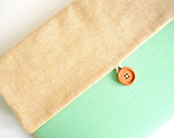May include: A light green fabric pouch with a beige flap and a brown button closure.