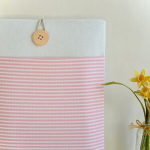 Op de afbeelding: Een roze en wit gestreepte laptophuls met een houten knoopsluiting.