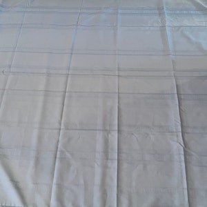 May include: A light blue bed sheet with a subtle striped pattern. The sheet is wrinkle-free and appears to be made of a soft, smooth fabric.