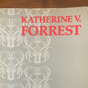 May include: A book cover with a gray background and a white floral pattern. The title "Dreams and Swords" is printed in red letters.