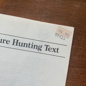 May include: A white booklet with the text "Treasure Hunting Text" printed in black. A price tag with the text "$6.95" and the number "49426" is attached to the booklet.
