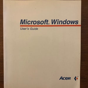 May include: A white cover for a Microsoft Windows User's Guide with the Acer logo in blue and red.