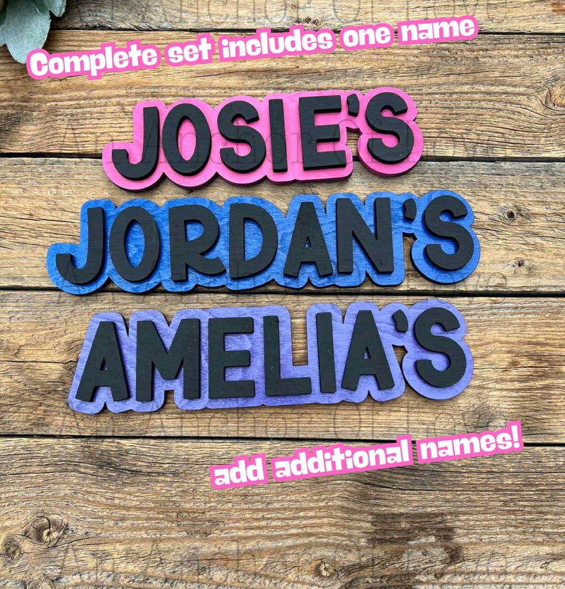 May include: Wooden name cutouts in pink, blue, and purple with black lettering. The names "JOSIE'S", "JORDAN'S", and "AMELIA'S" are displayed. Text at the top reads "Complete set includes one name" and at the bottom "add additional names!"