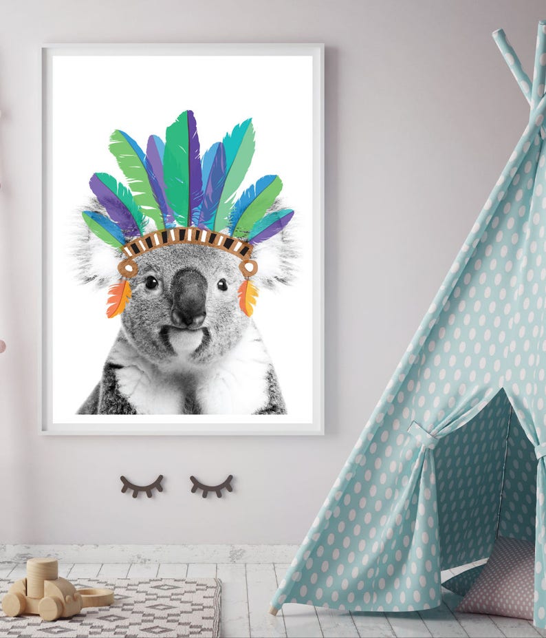 Puede incluir: Una foto en blanco y negro de un koala con un tocado de plumas de colores. El koala mira directamente a la c&aacute;mara con una expresi&oacute;n seria.