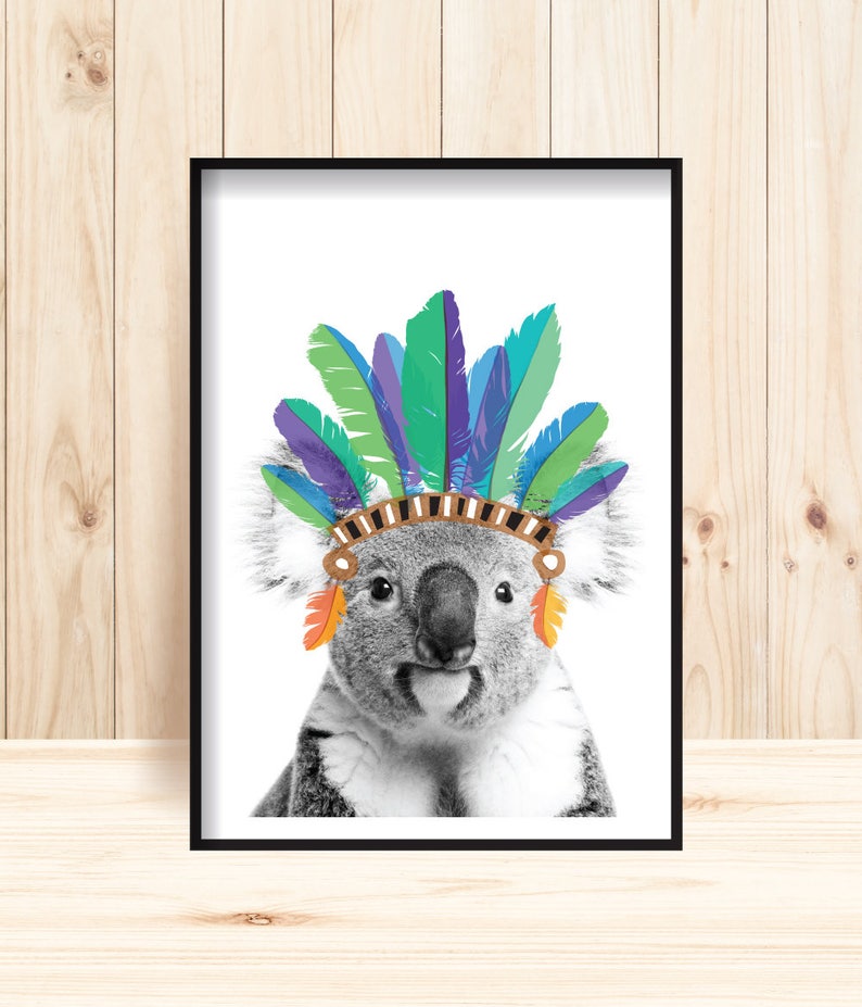 Puede incluir: Una foto en blanco y negro de un koala con un tocado de plumas de colores. El tocado est&aacute; hecho de plumas azules, verdes y moradas. El koala est&aacute; mirando directamente a la c&aacute;mara.
