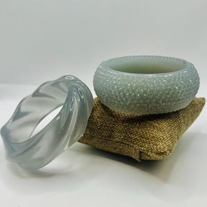 May include: Two grey plastic bangles. One bangle is smooth and the other has a textured surface.