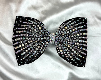 May include: A black velvet bow tie with iridescent rhinestones arranged in a geometric pattern.