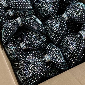 May include: A box filled with black fabric bows covered in iridescent rhinestones.