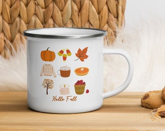 Puede incluir: Taza de esmalte blanco con borde plateado con un diseño de temática otoñal. La taza tiene un fondo blanco con ilustraciones de una calabaza, maíz dulce, una hoja, un suéter, una taza de café, una tarta de calabaza, un árbol, una vela, una cesta de arándanos y el texto "Hello Fall".