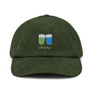 May include: A dark green corduroy baseball cap with an embroidered design of two glasses clinking and the word "cheers" underneath.