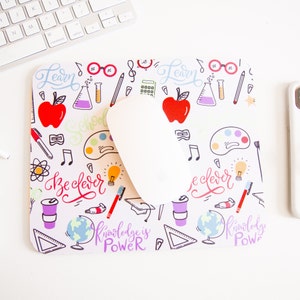 May include: White mouse pad with a colorful design featuring school supplies, musical notes, and the text "Learn", "Be Clever", and "Knowledge is Power".