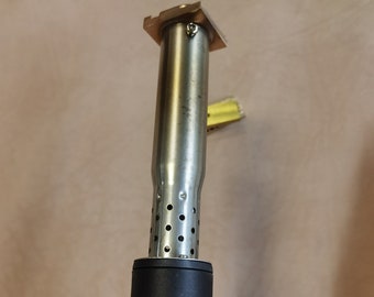 May include: A black and silver soldering iron with a temperature control dial that goes up to 500 degrees Celsius. The dial has markings for 200, 250, 300, 350, 400, 450, and 500 degrees Celsius. The soldering iron has a red light that is on.