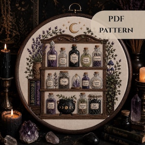 Puede incluir: Un bastidor de bordado circular con un diseño cosido de un estante de madera de tres niveles. Los estantes contienen varias botellas de vidrio con tapones de corcho, etiquetadas con texto que incluye Dreams, Moon Water, Night Shade y Frog's Breath.