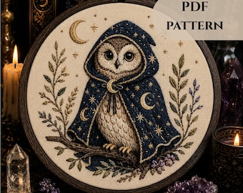 May include: A circular embroidery hoop containing a fabric panel with a stitched owl wearing a dark blue hooded cloak decorated with gold stars and crescent moons. The owl sits on a branch surrounded by embroidered leaves and flowers. Text reads PDF PATTERN.