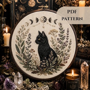 Peut inclure: Un tambour à broder contenant un panneau en tissu avec un chat noir entouré de fleurs sauvages brodées et un cycle de phases lunaires au-dessus. Le texte PDF PATTERN est visible dans le coin supérieur droit sur un fond sombre.