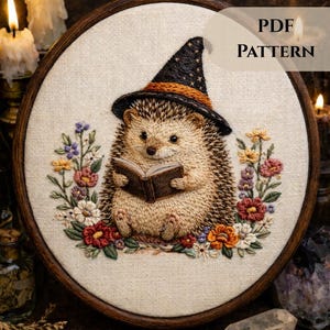 May include: Embroidered hoop art featuring a hedgehog wearing a witch's hat and reading a book, surrounded by colorful flowers. The text "PDF PATTERN" is displayed on the top right. The artwork is set against a neutral fabric background.