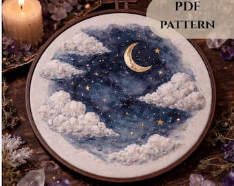 May include: A round embroidery hoop featuring a night sky scene with a crescent moon, stars, and fluffy clouds. The artwork is in shades of blue, white, and gold. The text "PDF PATTERN" is visible. The hoop is set against a dark wooden surface.