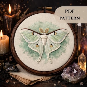 Peut inclure: Broderie d'un papillon de nuit dans un cercle en bois. Le papillon a des ailes vert pâle avec des détails marron et or, sur un fond vert clair. Le texte "PDF PATTERN" est visible. La broderie est sur un tissu crème.