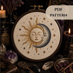 以下が含まれることがあります： 「PDF PATTERN」の文字が入った、太陽と月のデザインの丸い刺繍枠。太陽は金色、月は濃い青色。小さな星がデザインを囲んでいます。デザインは円形です。