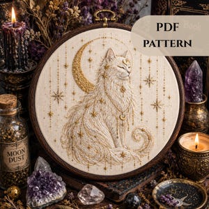 Peut inclure: Un motif de broderie détaillé représentant un chat blanc orné d'un croissant de lune et d'étoiles dorées. Le motif est encadré dans un cercle en bois, avec le texte "PDF PATTERN". L'image est entourée de bougies, de cristaux et d'une bouteille "MOON DUST".
