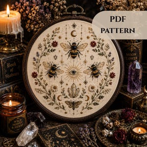 May include: An embroidered hoop with a design of bees, flowers, and celestial motifs. The text "PDF PATTERN" is visible. The color scheme includes beige, brown, black, and gold.