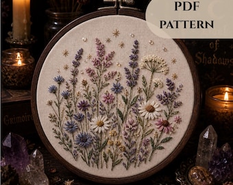 May include: A detailed embroidery hoop featuring a floral design with lavender, daisies, and other wildflowers in shades of purple, pink, and white. The text "PDF PATTERN" is visible. The embroidery is set in a wooden hoop.
