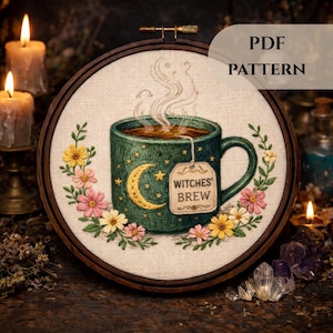Może przedstawiać: Haft na tamborku przedstawiający turkusowy kubek z księżycem i gwiazdami, wypełniony herbatą i oznaczony napisem "Witches' Brew". Projekt otoczony jest kwiatami i liśćmi. Tekst "PDF PATTERN" znajduje się w prawym górnym rogu.