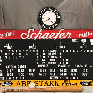 May include: A vintage baseball scoreboard with a clock, a baseball bat, and a baseball. The scoreboard displays team statistics, including runs, hits, and errors. The clock reads "Official Time Bulova". The sign reads "Schaefer real beer".